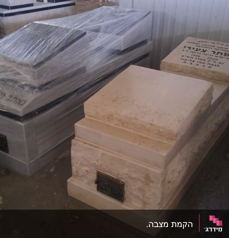 מצבות עטופות בניילון במחסן, אחת עם כיתוב בעברית